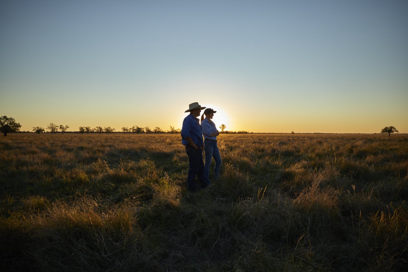 Two sheep producers standing in open pasture at sunset, central west New South Wales